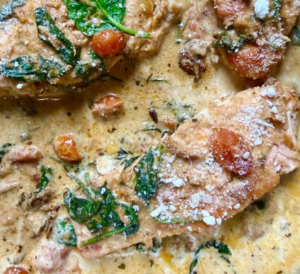 Pan-seared salmon finished in creamy Tuscan sauce with spinach and cherry tomatoes