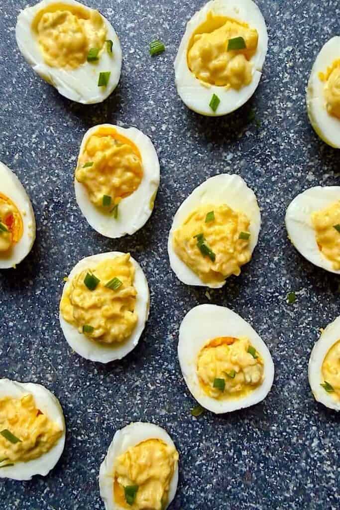 Low carb deviled eggs arranged on a speckled surface, topped with creamy yolk filling and fresh chives, perfect for a diabetic-friendly appetizer