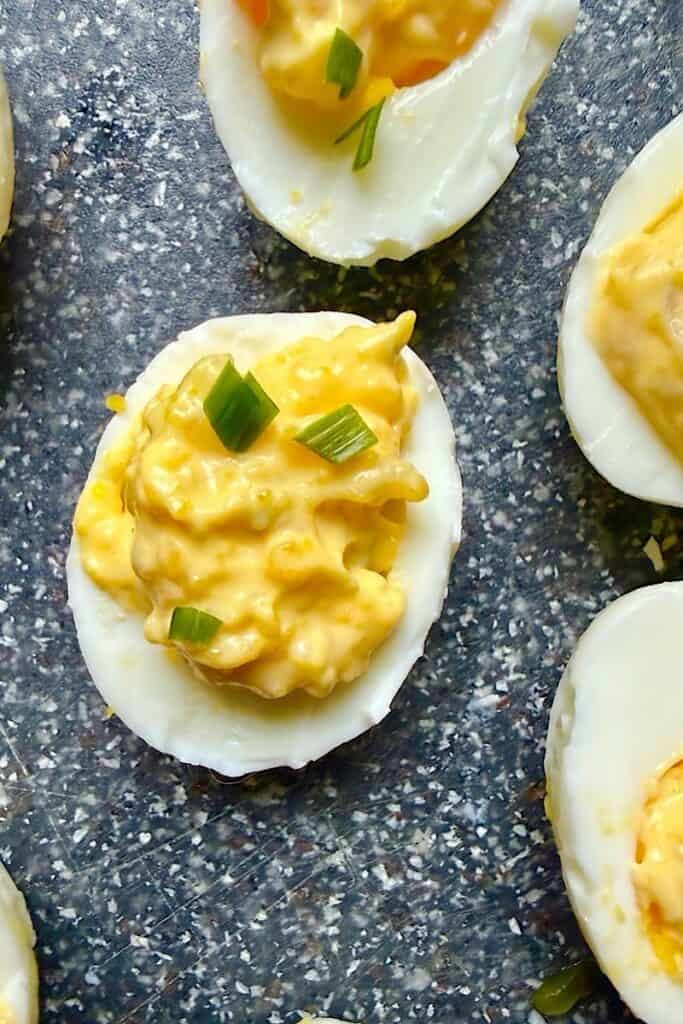 Close-up of a diabetic-friendly deviled egg with smooth egg whites, creamy mustard mayo yolk filling, and chopped green onions