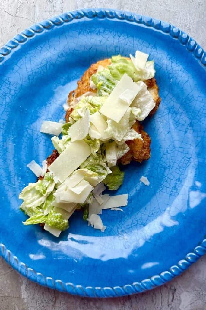 Crispy air fryer chicken breast cutlet with Caesar salad on top