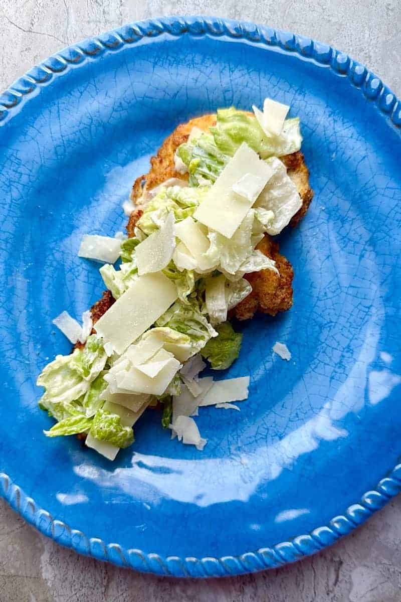 Crispy air fryer chicken breast cutlet with Caesar salad on top