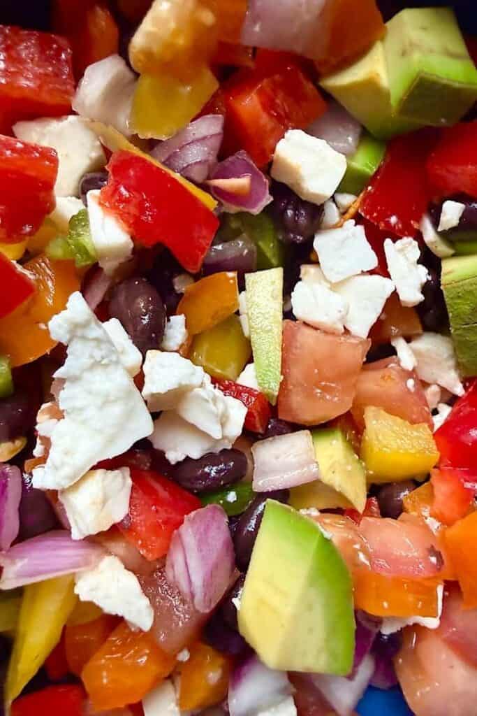 Close-up of low-carb cowboy caviar with diced avocado, black beans, bell peppers, red onion, tomatoes, and cotija cheese mixed together
