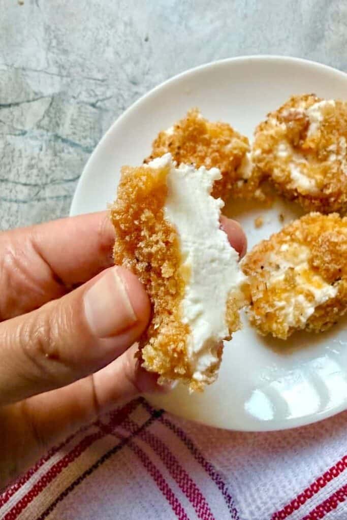 Opened fried goat cheese over a plate of goat cheese 