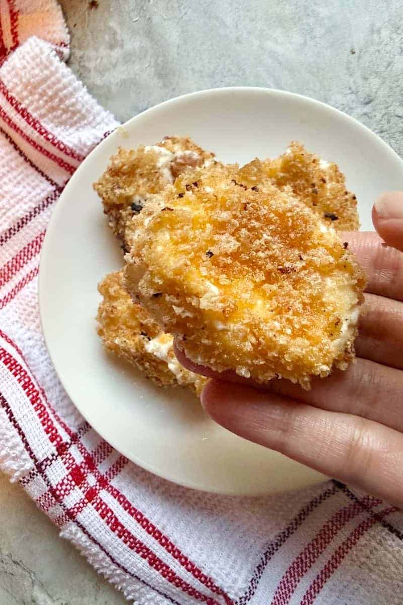 Breaded goat cheese rounds coated in crushed pork rinds before frying