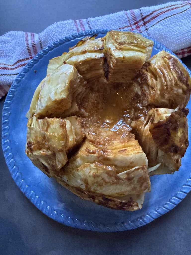 Whole viral cabbage boil baked with Cajun butter, garlic, and chicken bouillon, sliced into wedges with melted seasoned butter in the center.